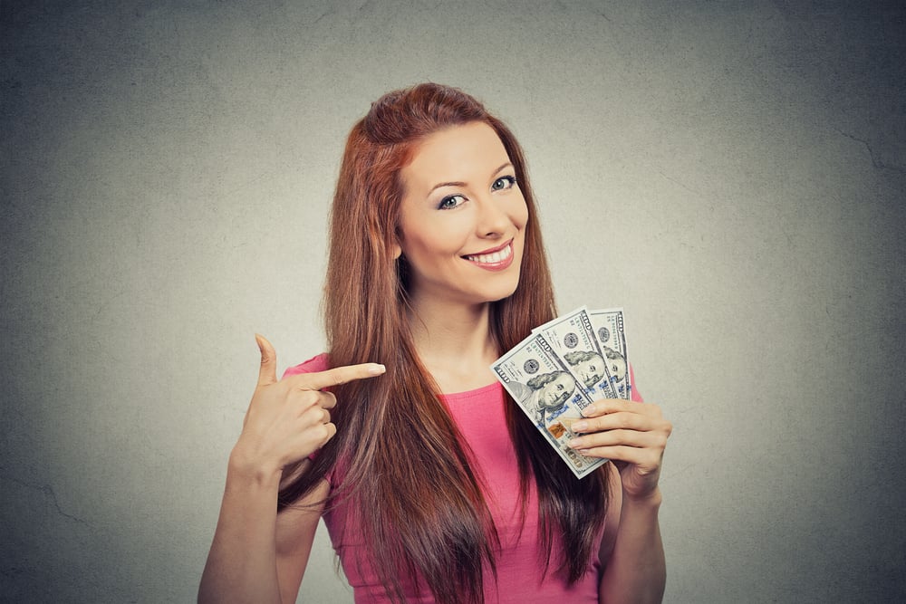 Closeup portrait super happy excited successful young business woman holding money dollar bills in hand isolated grey wall background. Positive emotion facial expression feeling. Financial reward-1